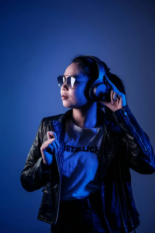 a girl wearing a leather jacket and sunglasses listening to music