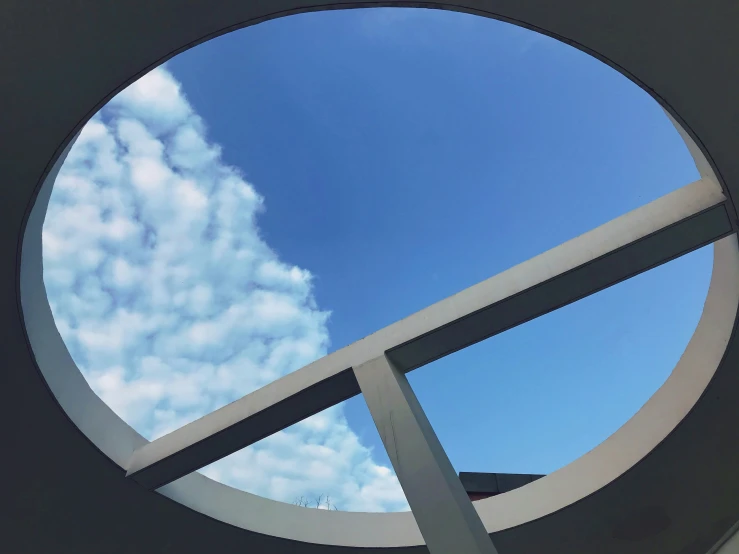 a circular window with a sky background and a circular metal structure