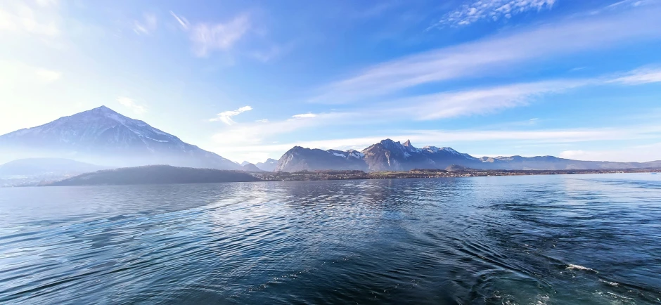 a boat on the water near some mountains and blue sky