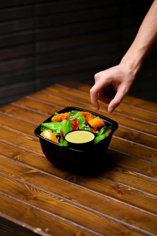 someone reaching for some food from a black container