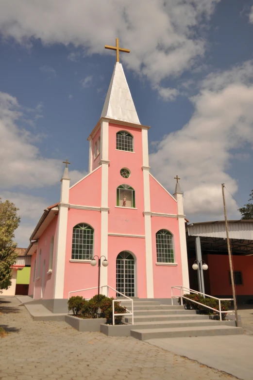 a pink colored church building with a cross on top