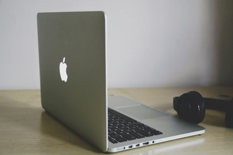 an apple laptop with a pair of headphones near it