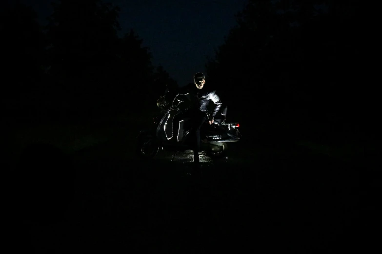 the dark is on and a motorcycle rider stands beside it