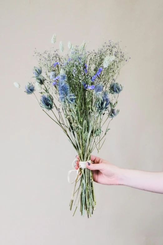 a woman holding up a bunch of dried flowers