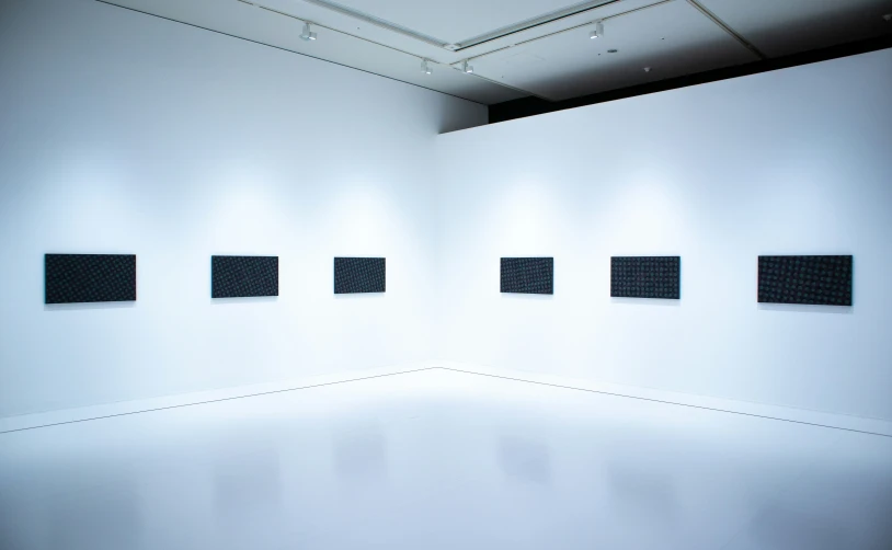 a white room with four black squares hanging