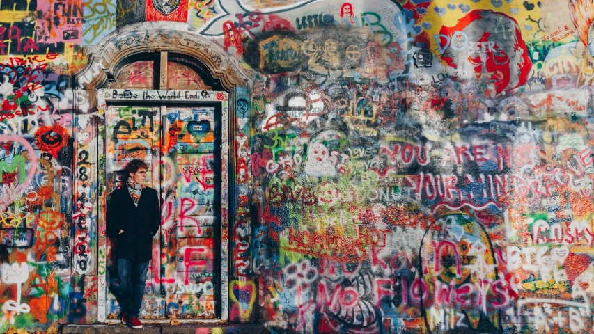 a man standing in a doorway covered in grafitti