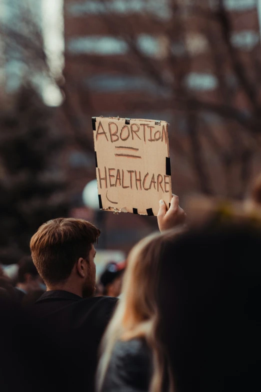 a man holding up a cardboard sign in the air