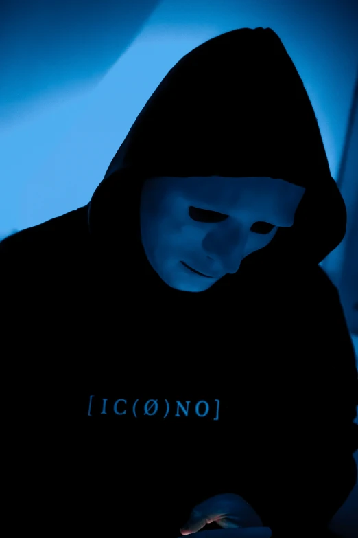 a guy in a black hoodie with the words iconoi on it is texting on his phone