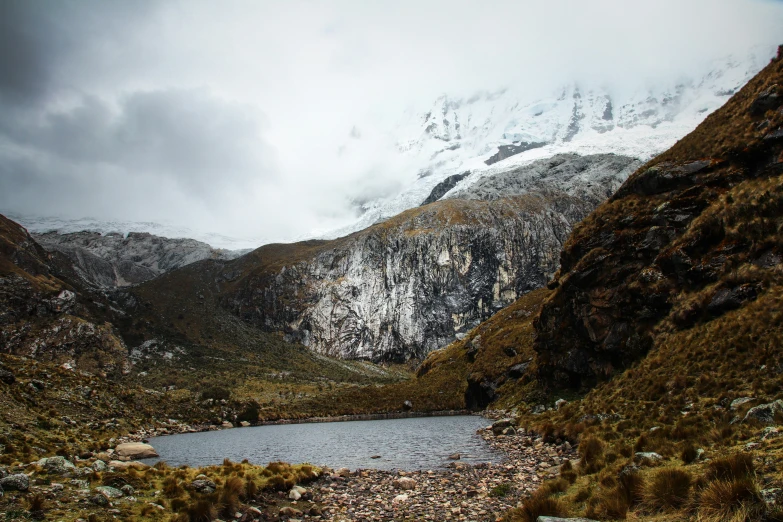 there is a small lake on the side of the mountains