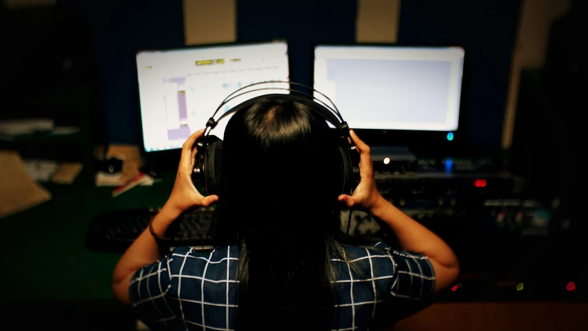 a woman with a pair of headphones is looking at the monitor