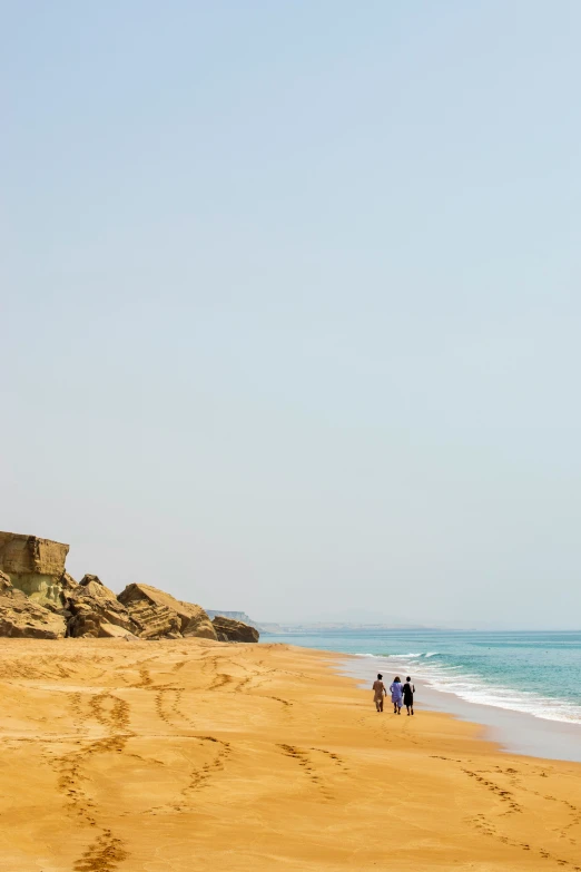 some people walking on a sandy beach near the ocean