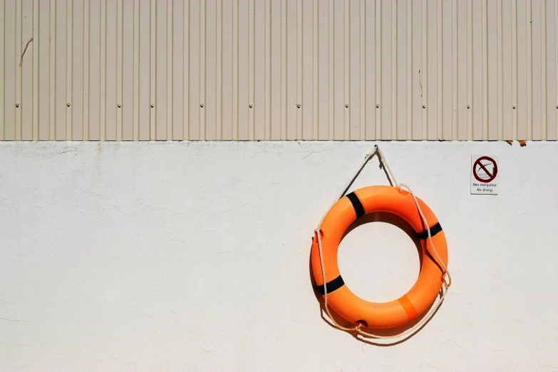 a small orange life preserver hanging on the wall of a building