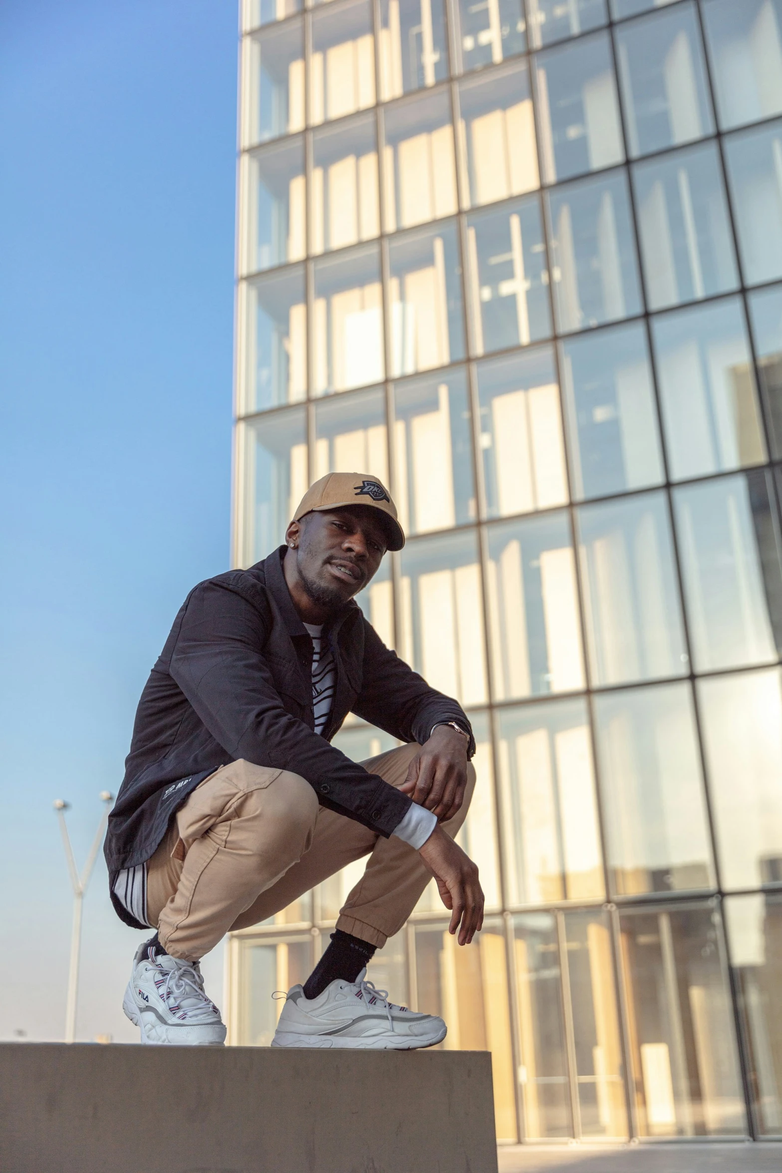 a man poses in front of a very tall glass building