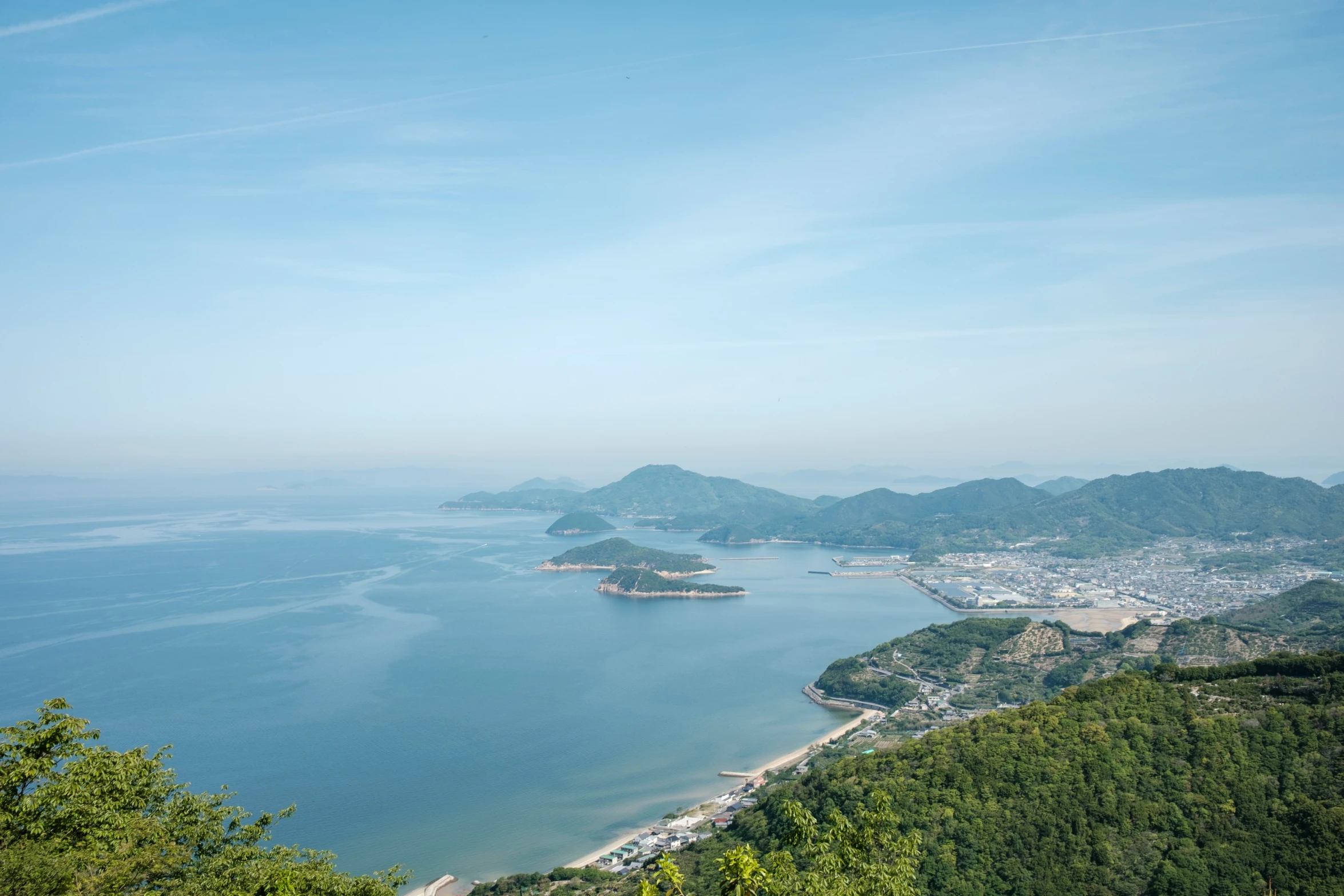 a lake surrounded by hills and trees on a clear day