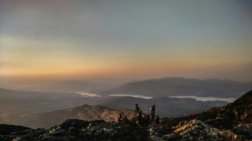 a person is sitting on a mountain near a forest