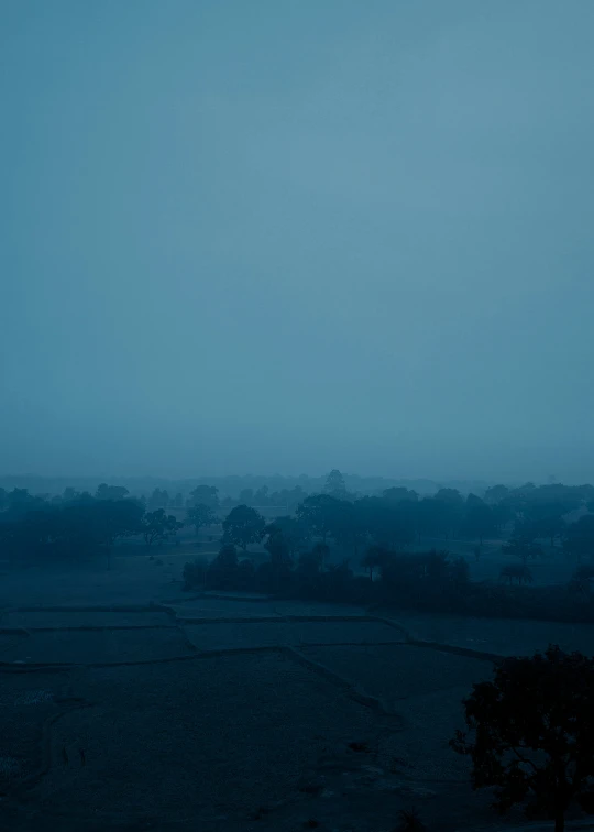 a hazy sky over some trees and houses