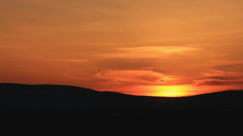 sunset with two birds flying over hills