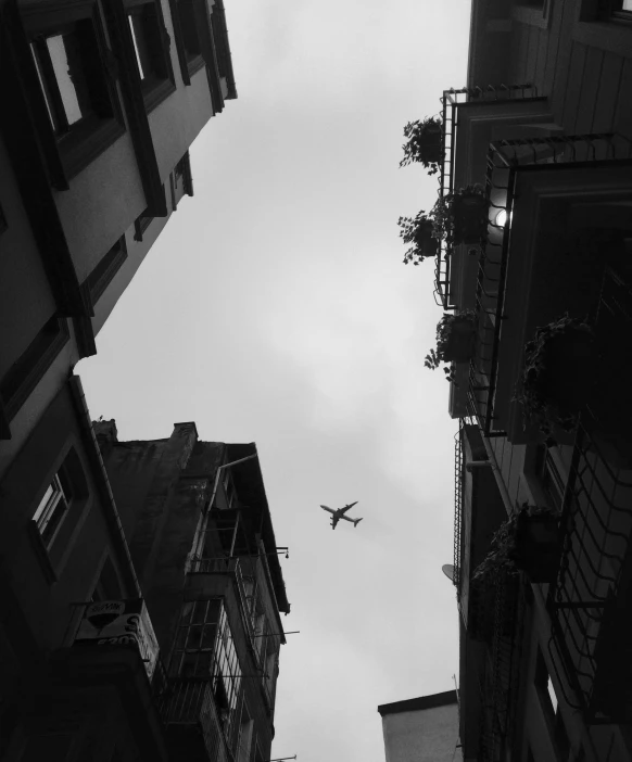 an airplane flying through the sky between buildings