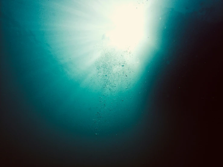 a blue ocean with water bubbles and sun rays