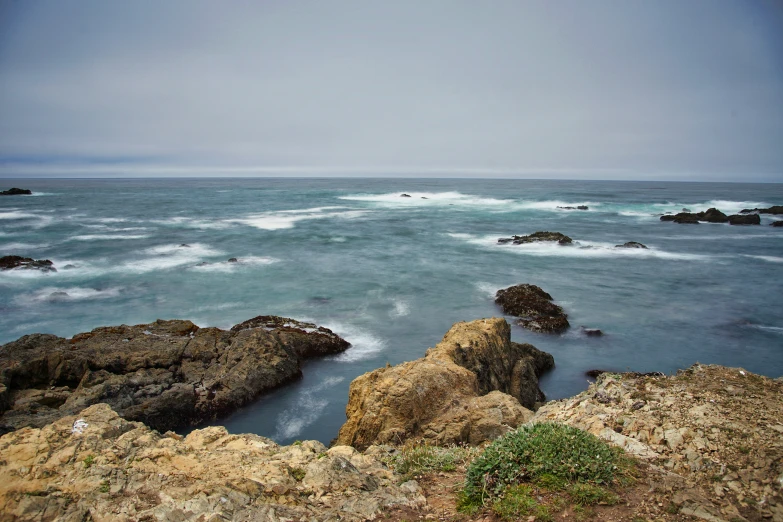 a body of water with waves coming off the rocks