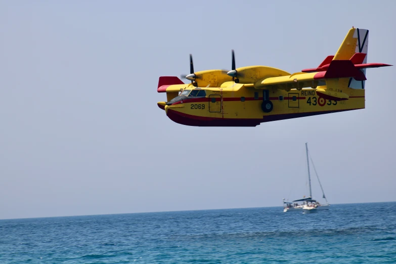 the yellow airplane flies over the water as a small boat passes by