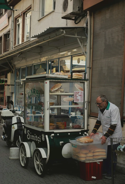 a man standing outside a food cart on the side of the road