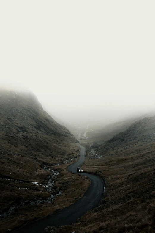 the road is going through the mountains covered in fog