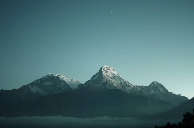 a snowy mountain range in the foreground with some trees below