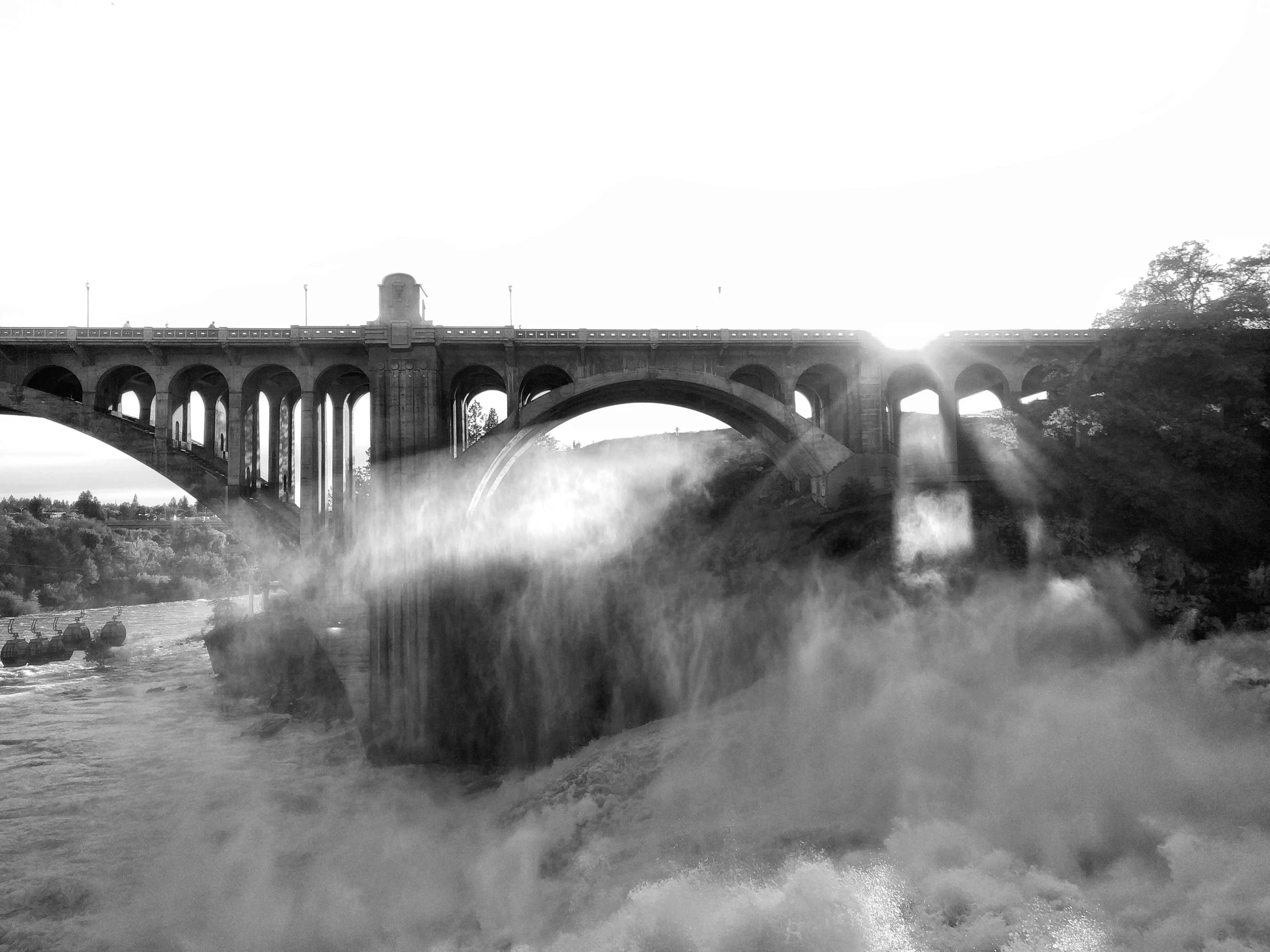 smoke is rising from the water near a bridge