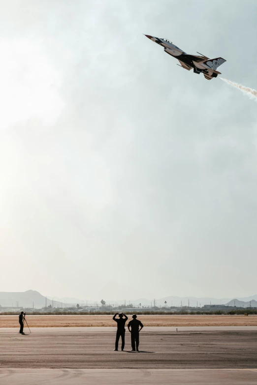 two guys are watching the fighter jet fly