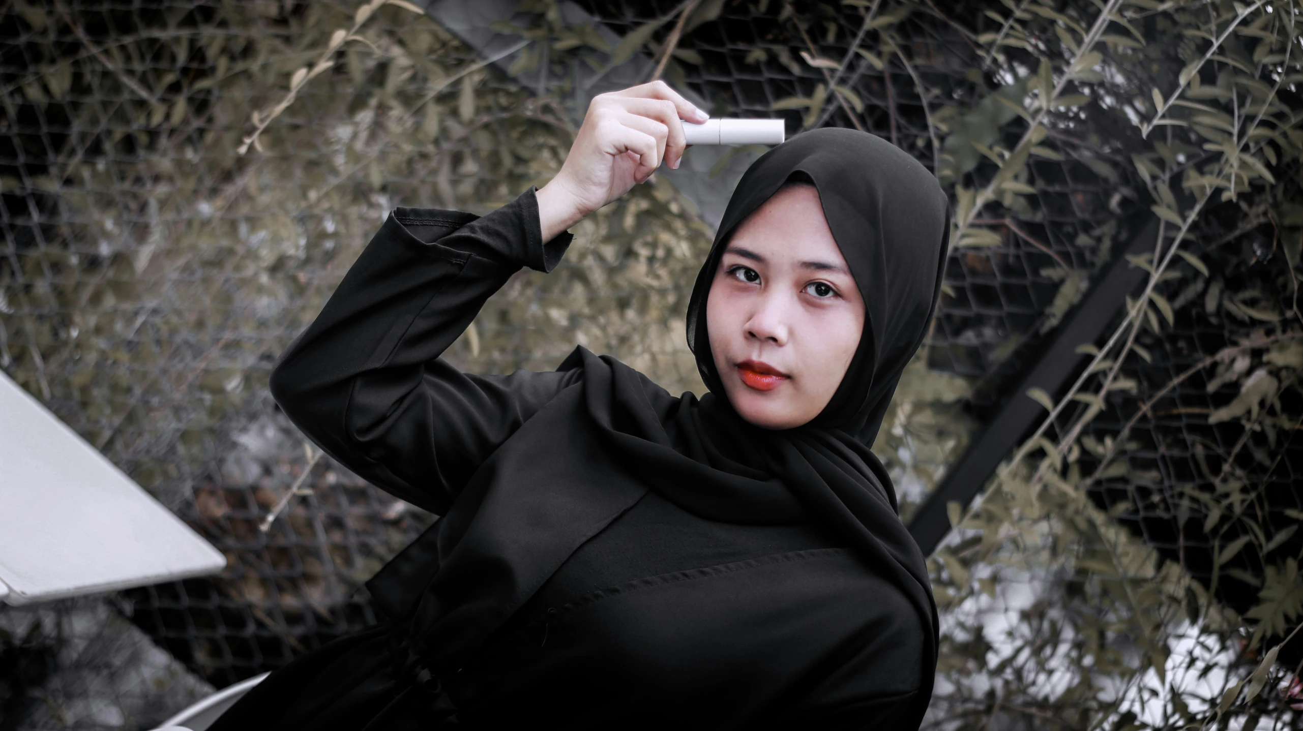 a woman wearing a hoody standing near a fence