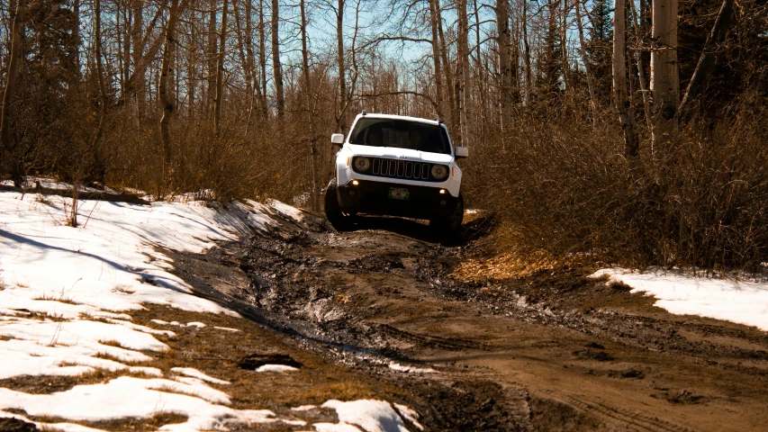 a jeep drives through some snow in the woods