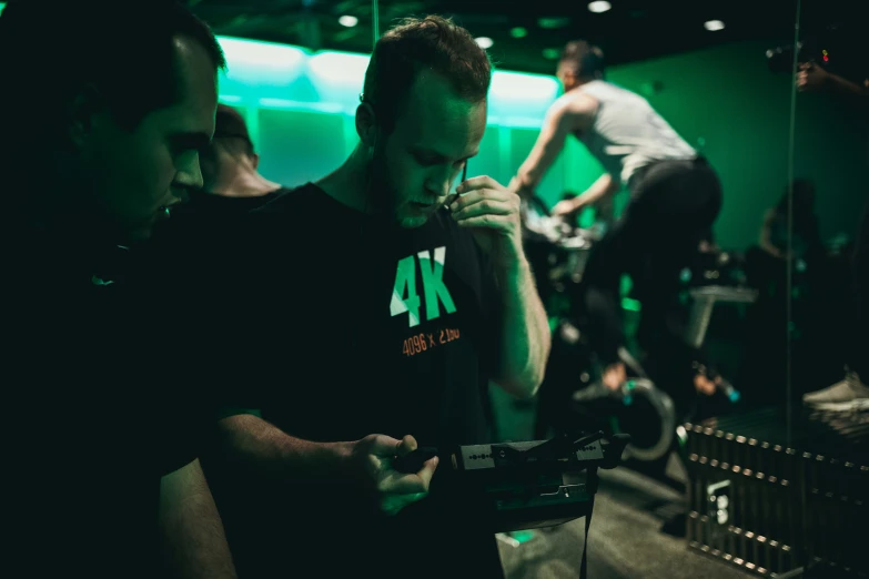 three men looking at an electronic device in a room