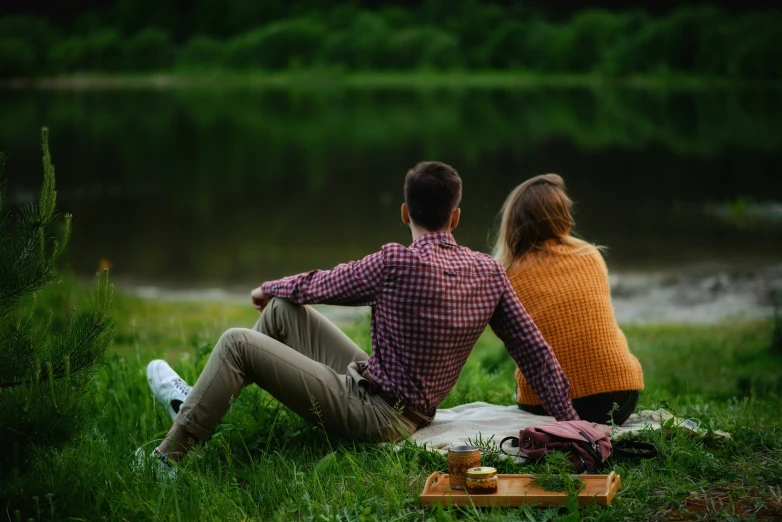 two people sitting on the grass with a picnic