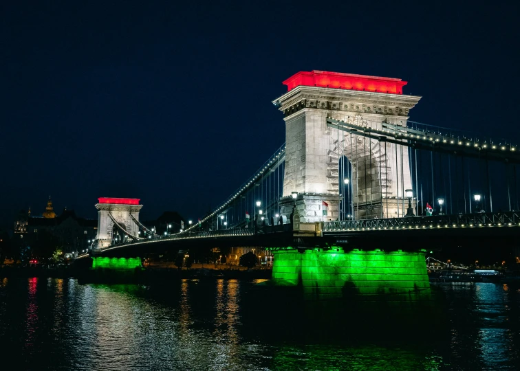 a bridge lit up at night with the lights turned green