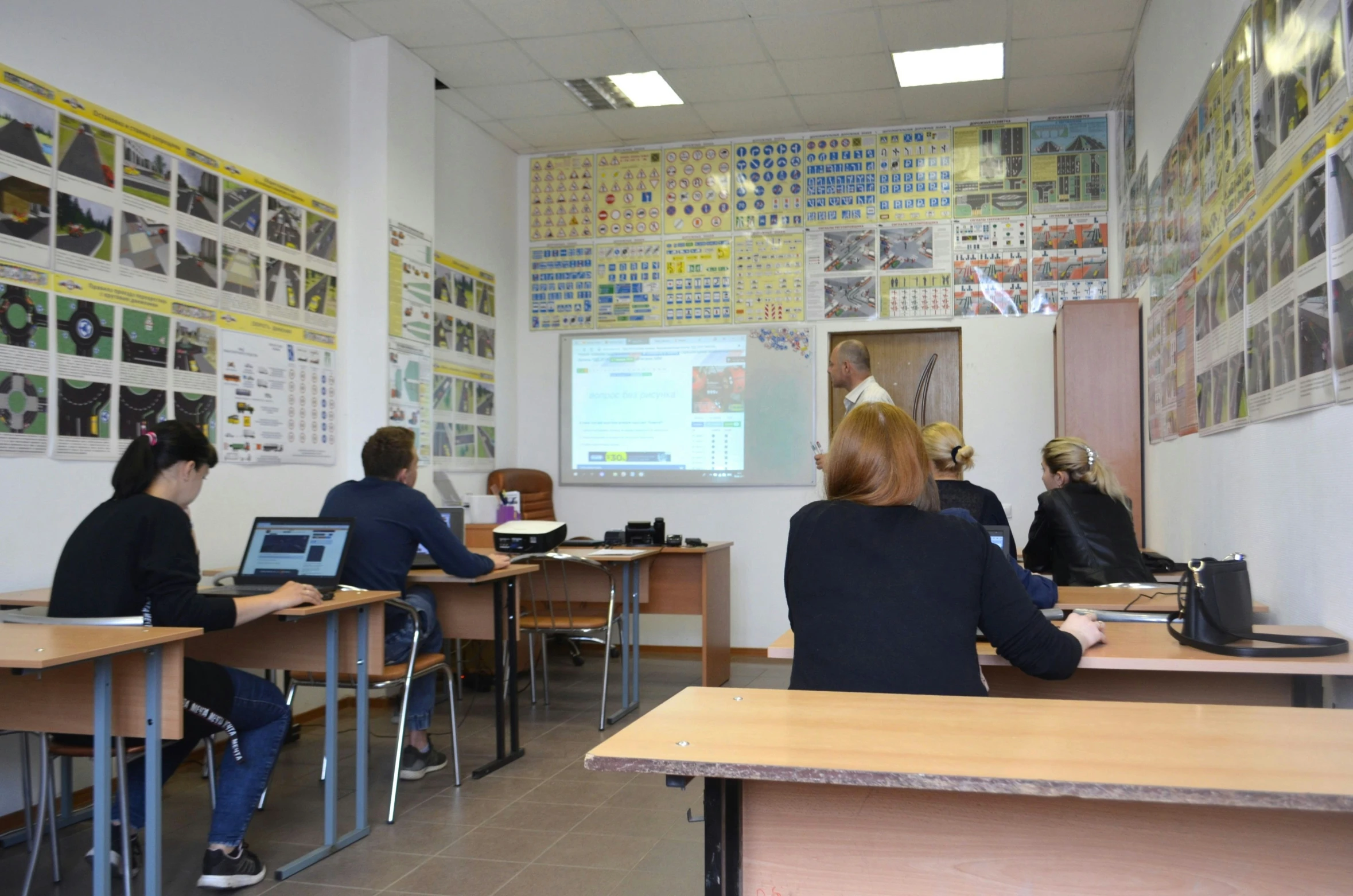 a class room with wooden desks and pictures on the wall