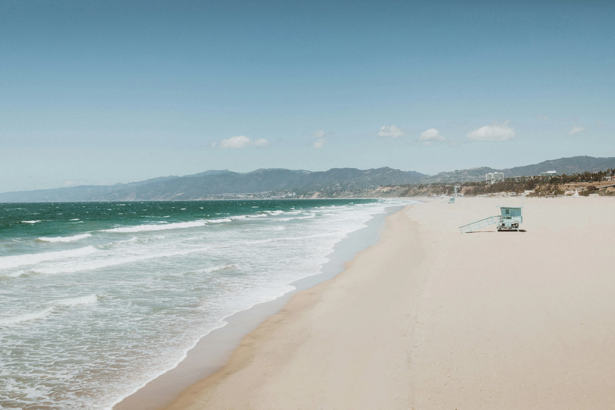 a view from a beach with a lawn chair next to the ocean