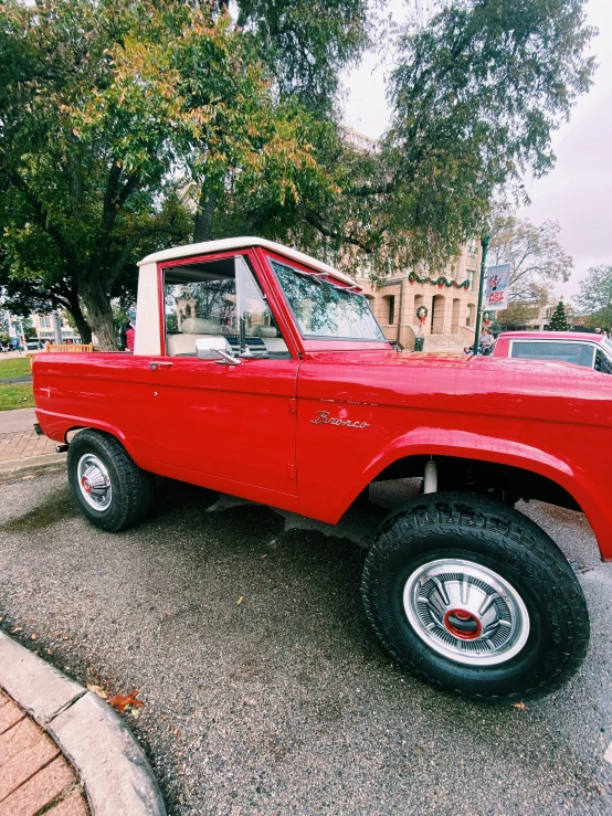 a classic red truck with large tires in a parking lot