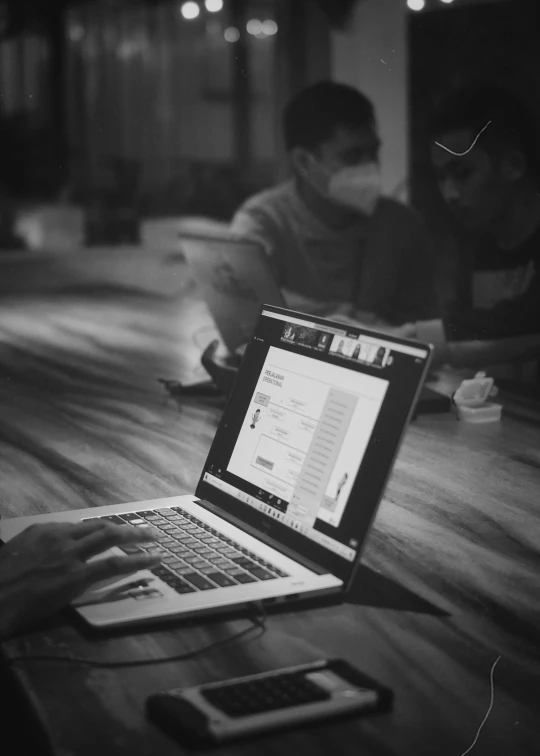 a black and white po shows people sitting around a table on laptops