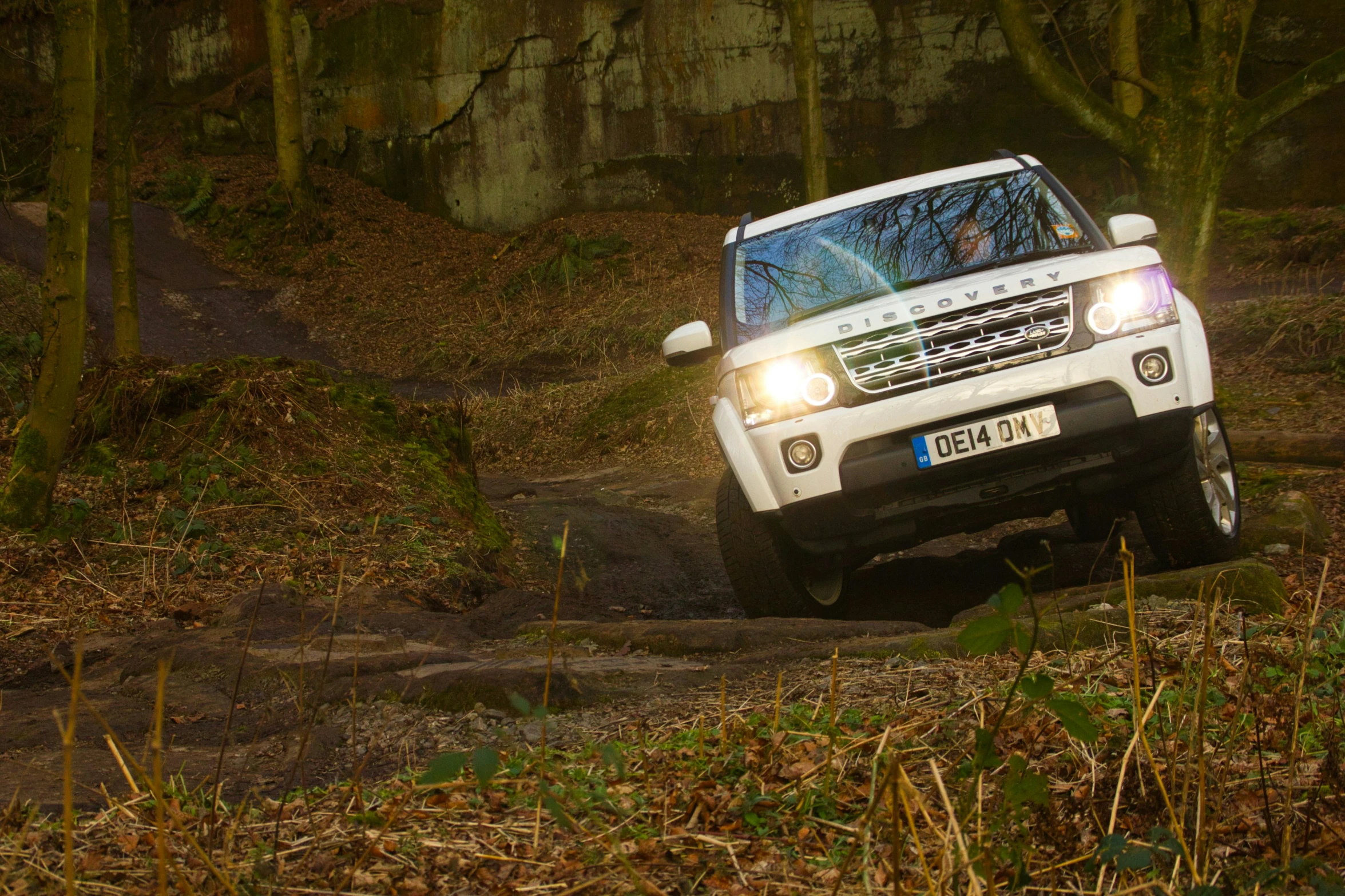 a white car driving on a trail in the woods