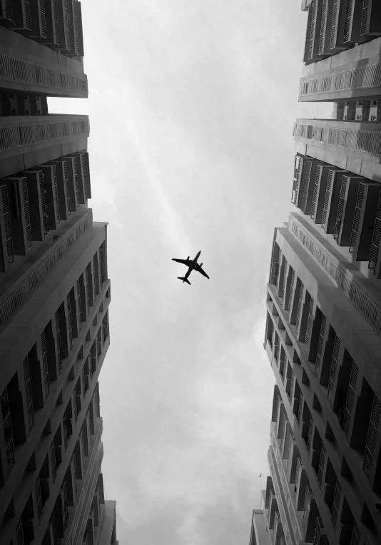 an airplane flying between two buildings on an overcast day