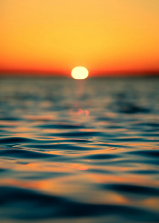 the sun setting over water and reflecting the horizon