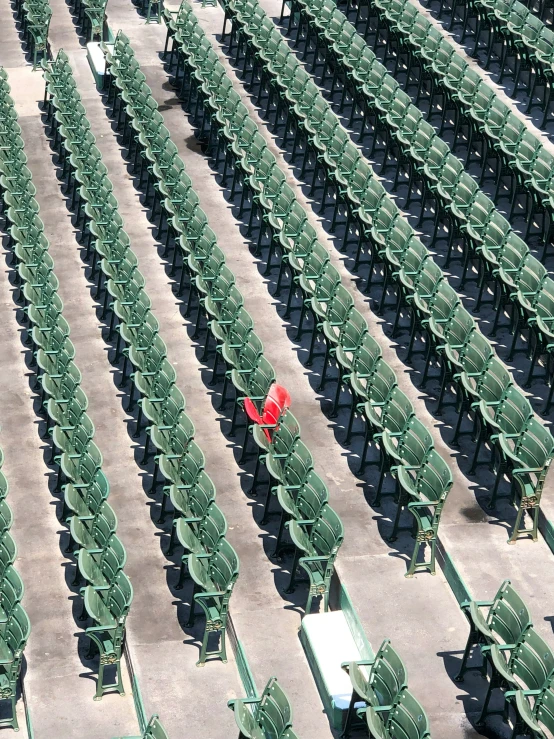 an empty stadium full of green chairs and one red bench