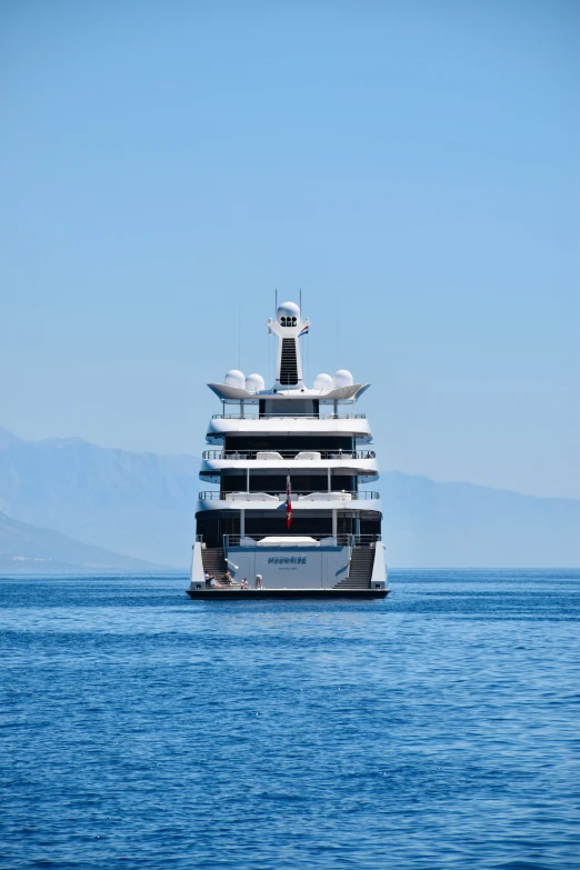 a large boat floating through the ocean next to some mountains