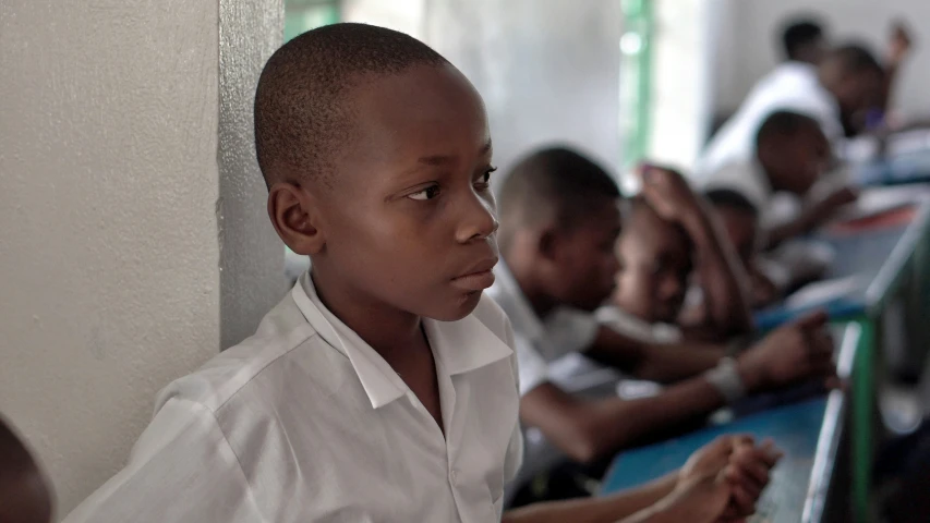 young children are sitting in a row at a desk