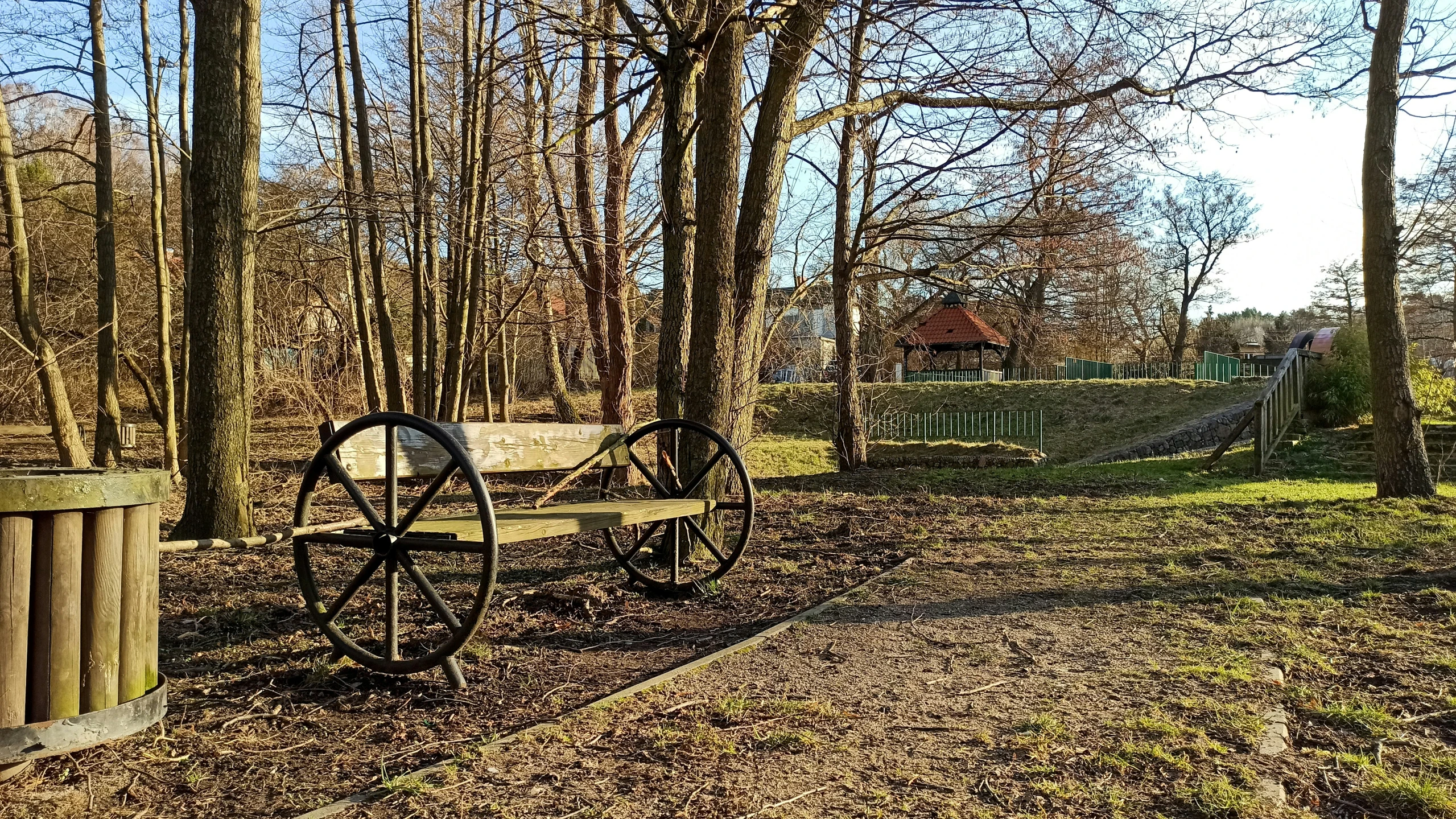 a wooden wagon sits on a dirt path next to trees