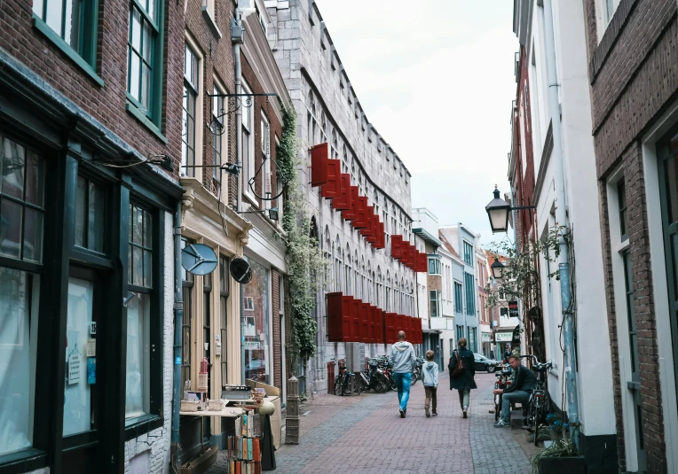 people walk down a brick sidewalk between two buildings