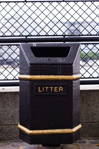 a black and yellow litter bin sitting outside
