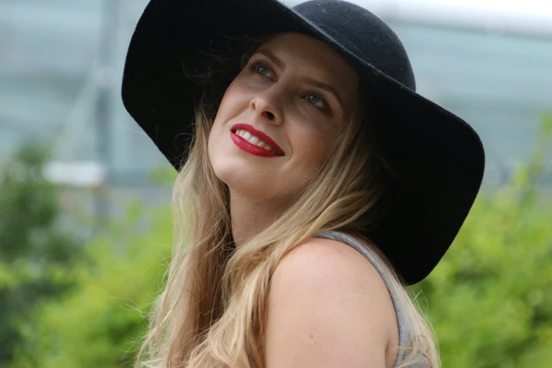 a girl in a floppy hat standing outdoors