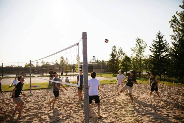 a group of people playing volleyball on top of sand